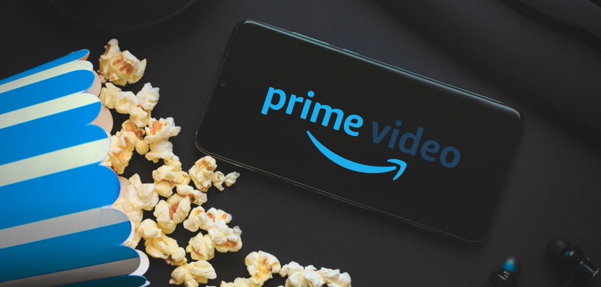 Logo von Amazon Prime Video auf einem Handy, daneben eine TÃ¼te Popcorn.