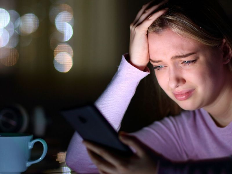 Frau blickt weinend auf ihr Smartphone