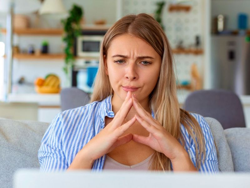 Frau blickt nachdenklich auf ihren Laptop