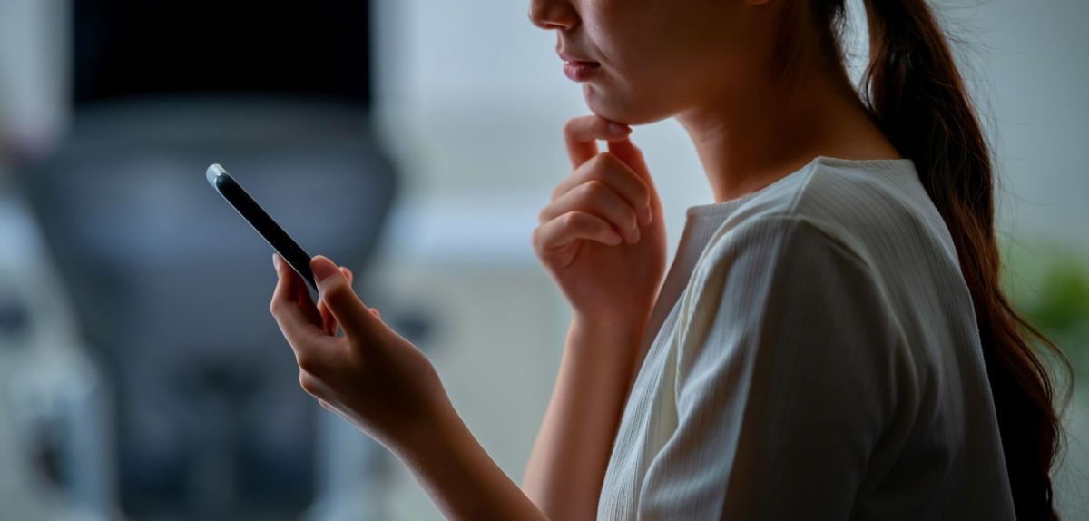 Frau blickt besorgt auf ihr Smartphone