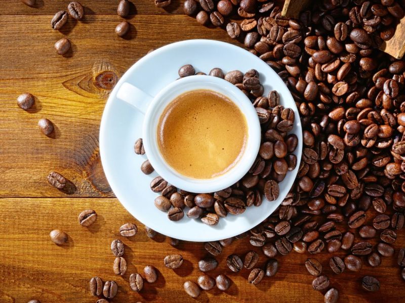 Eine Tasse Kaffee nebst einem Sack mit Kaffeebohnen.