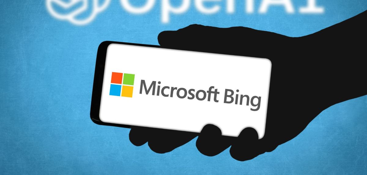 Logo für Microsoft Bing auf einem Handy-Display, dahinter das Logo von OpenAI.