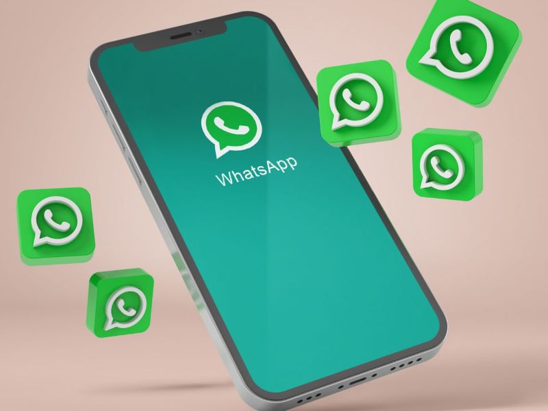 WhatsApp-Logo auf einem Handy, drumherum fliegen mehrere WhatsApp-Symbole.