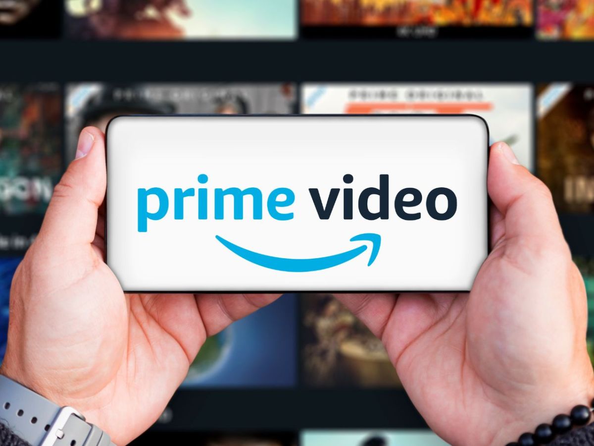 Amazon Prime Video-Logo auf einem Handy, dahinter Streaming-Kacheln.