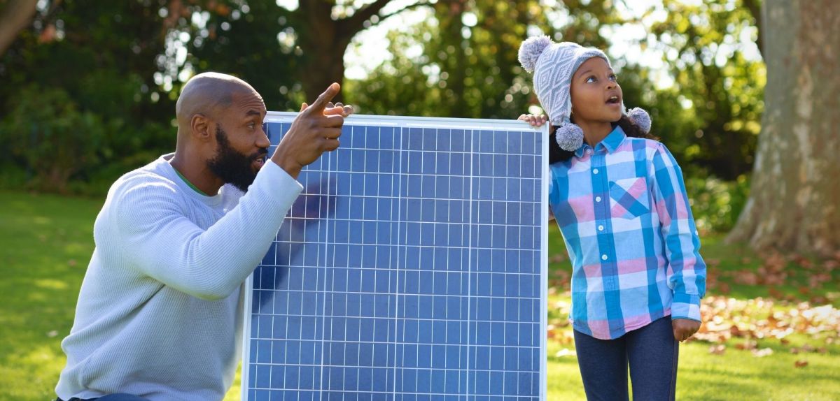Mann zeigt seiner Tochter eine kleine Solaranlage
