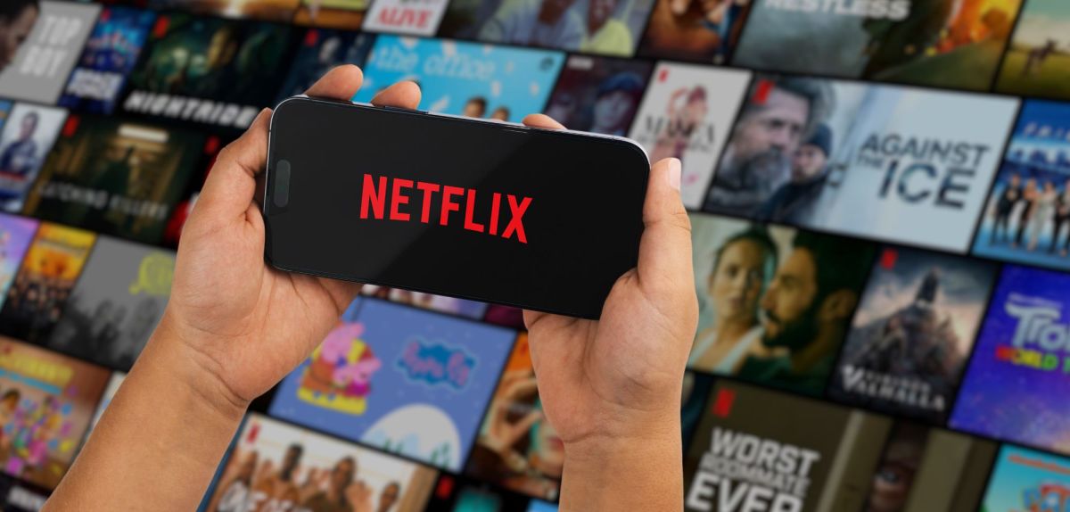 person hält handy mit netflix logo