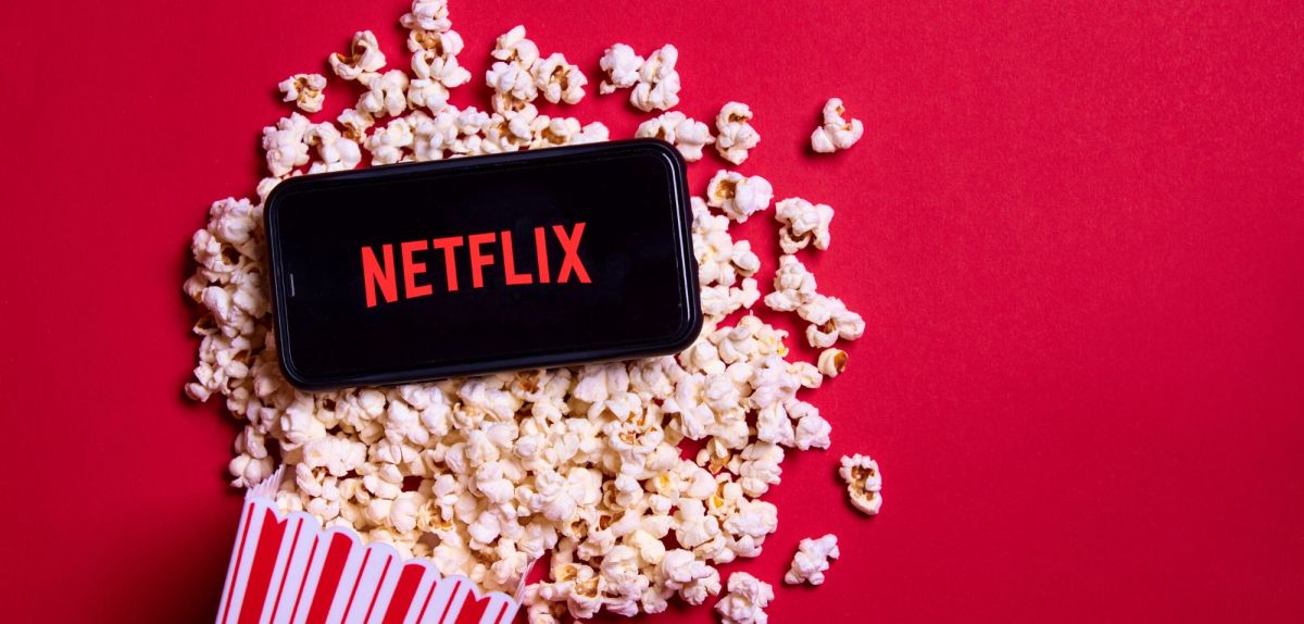 Netflix-Logo auf einem Handy, dadrunter Popcorn.