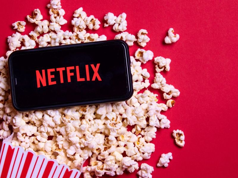 Netflix-Logo auf einem Handy, dadrunter Popcorn.