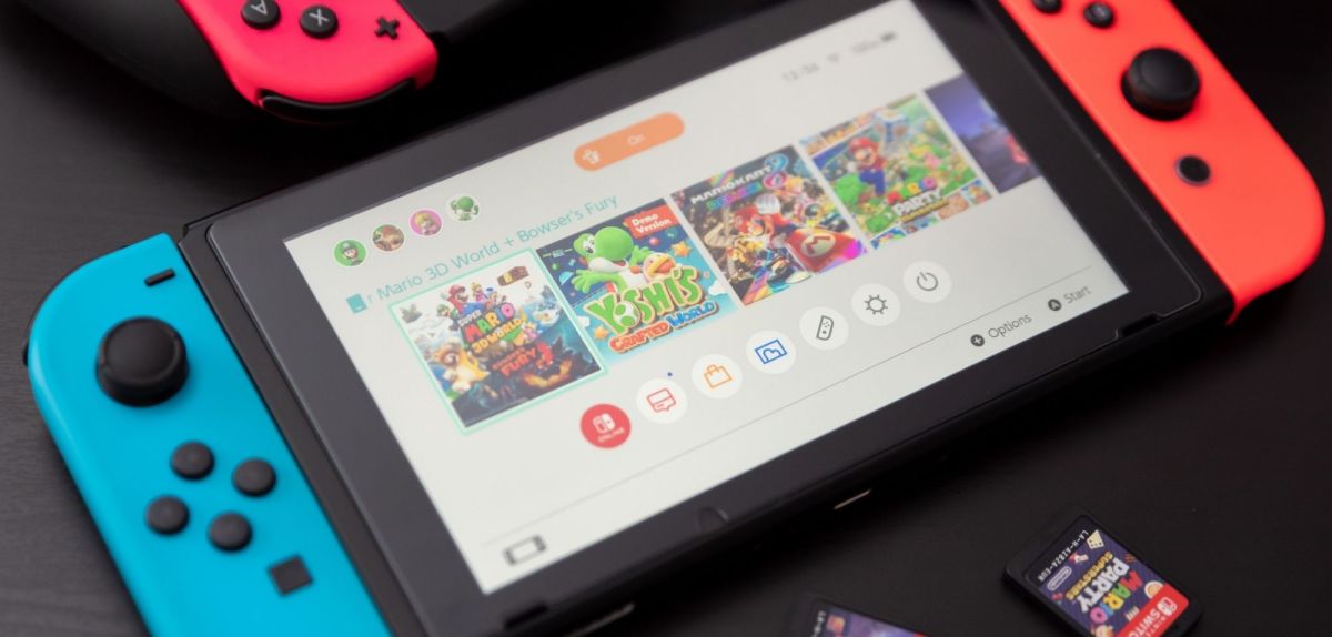Eine eingeschaltete Nintendo Switch, auf dem Display sind Kacheln für verschiedene Spiele zu sehen.