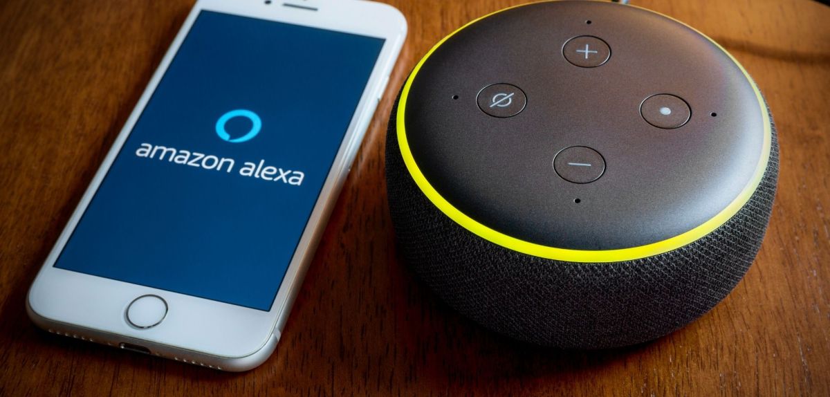 Amazon Echo Dot neben einem Handy mit Alexa-Symbol.