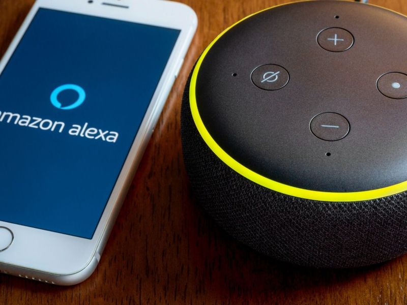 Amazon Echo Dot neben einem Handy mit Alexa-Symbol.