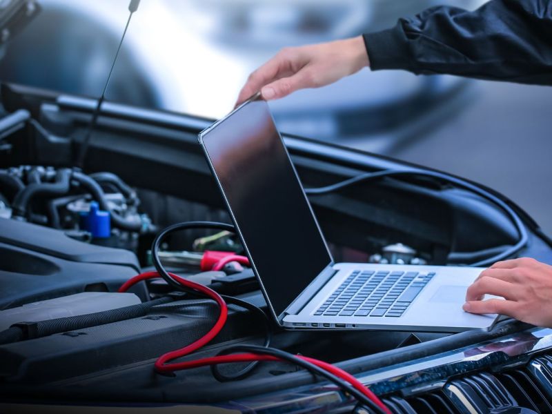 Laptop auf dem Motorraum eines Autos