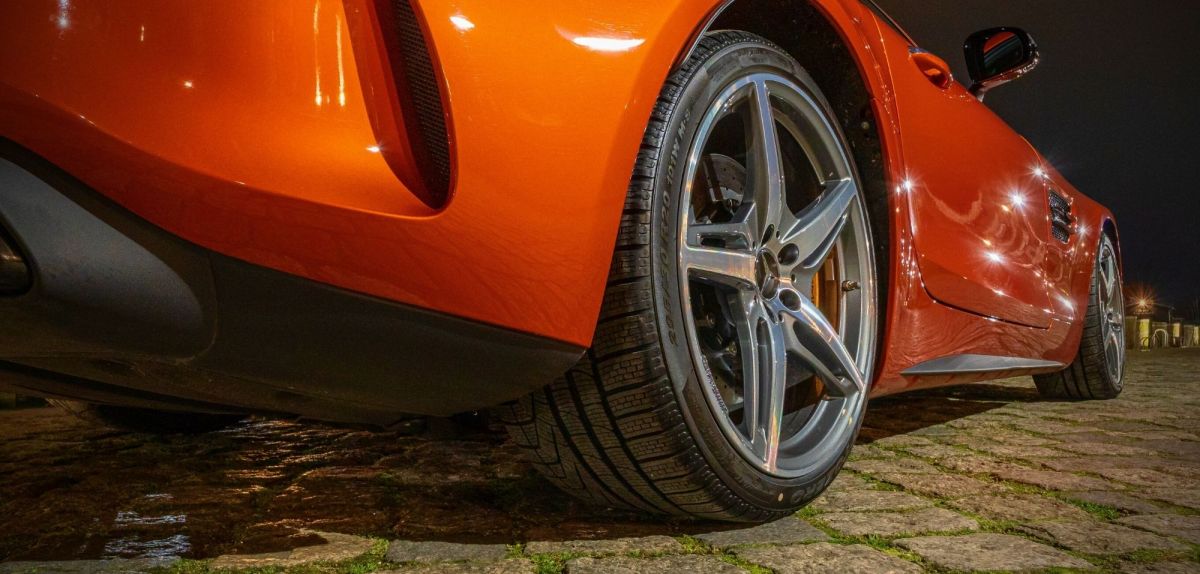 Nahaufnahme des Reifens eines orangenen Sportwagens