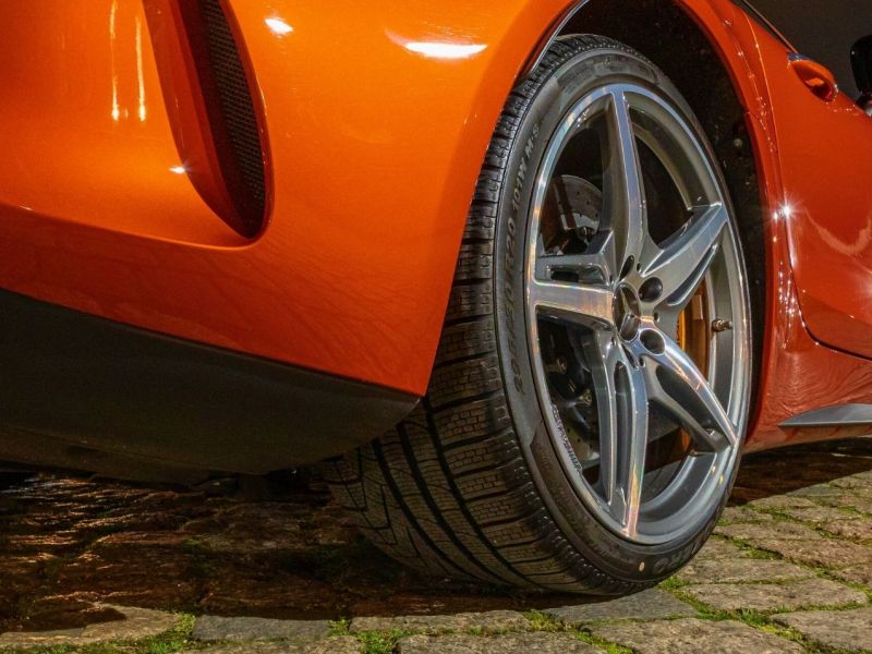 Nahaufnahme des Reifens eines orangenen Sportwagens