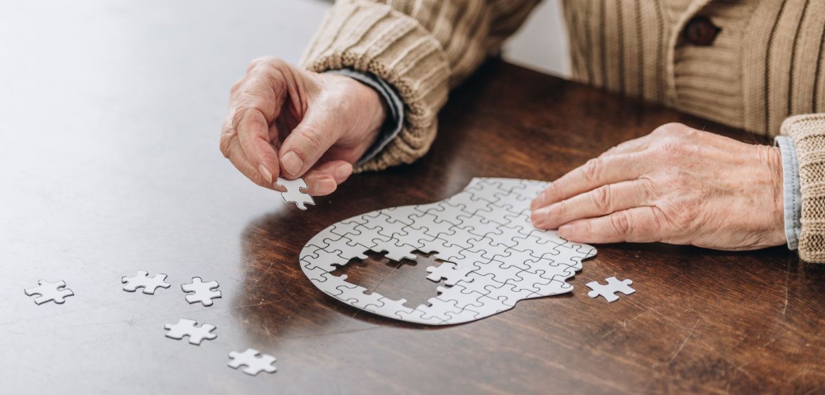 Alte Frau puzzelt als Symbolbild für Demenz