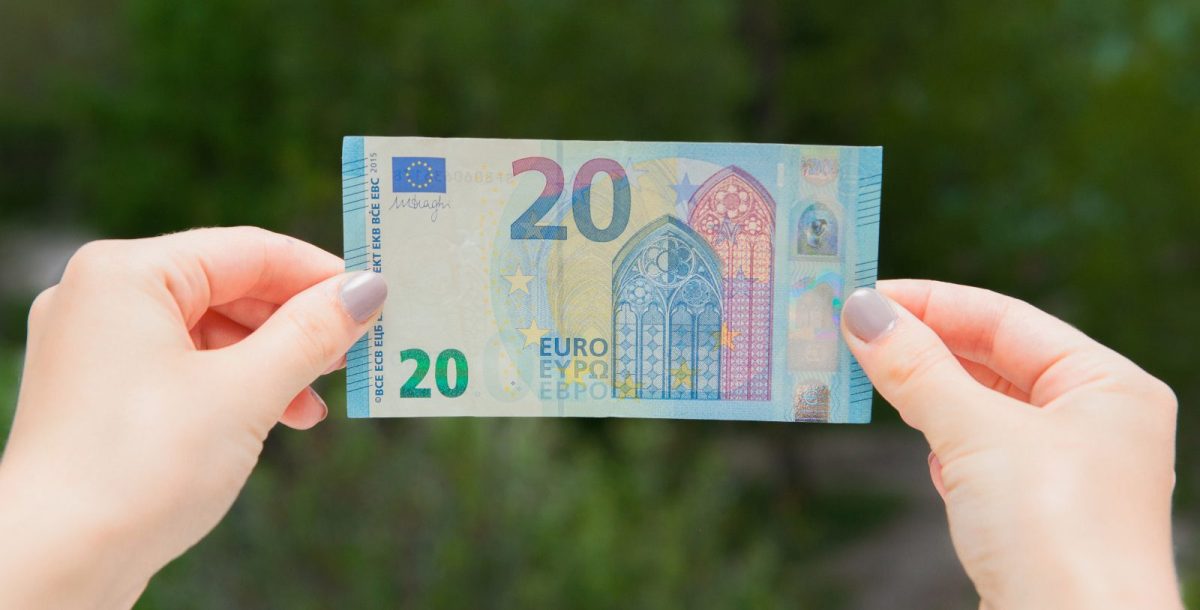 Frau hält einen 20-Euro-Schein in der Hand.