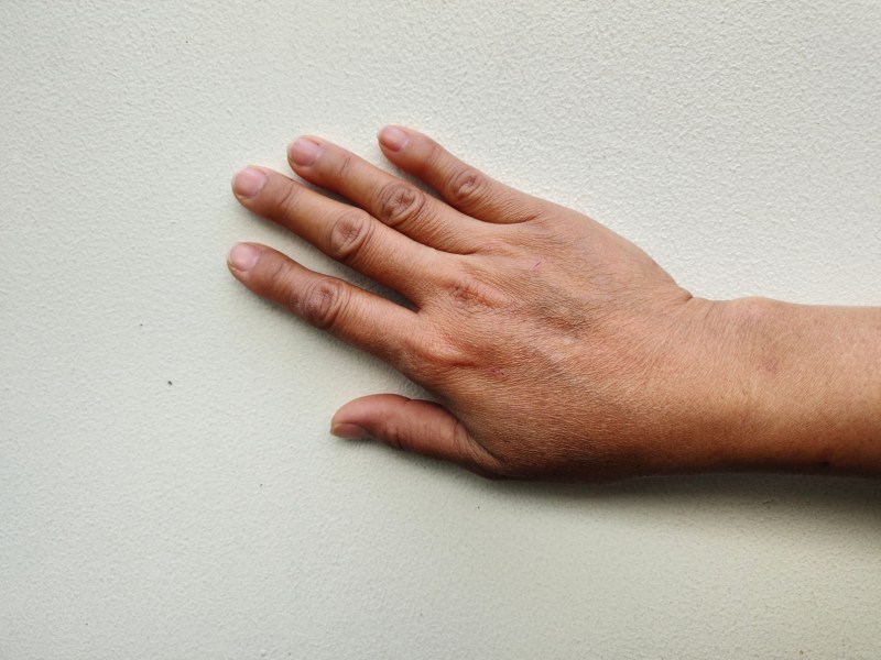 Hand vor einer Wand