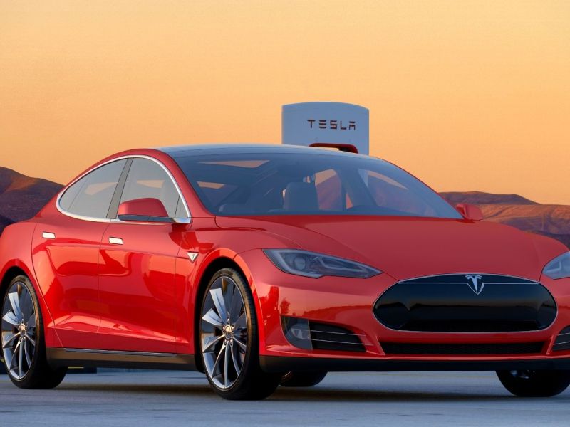 Ein Tesla-Auto vor mehreren Ladesäulen.