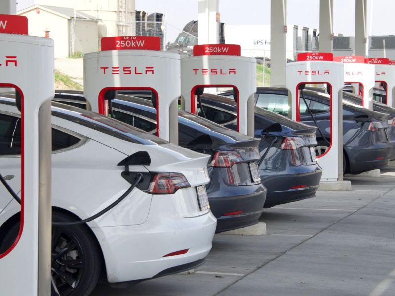 Eine Reihe Autos von Tesla an Ladesäulen des Unternehmens.