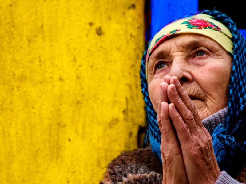 Frau betet vor einer gelb-blauen Wand