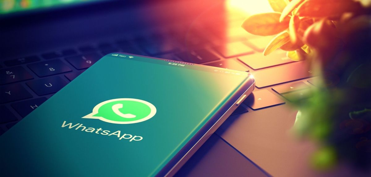 WhatsApp-Logo auf einem Handy, das auf einem Laptop liegt.