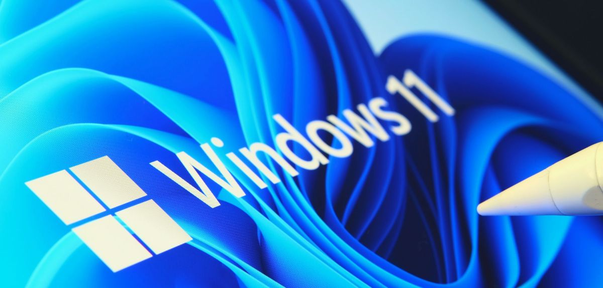 Windows 11-Logo auf einem Bildschirm und ein Stift im Vordergrund.