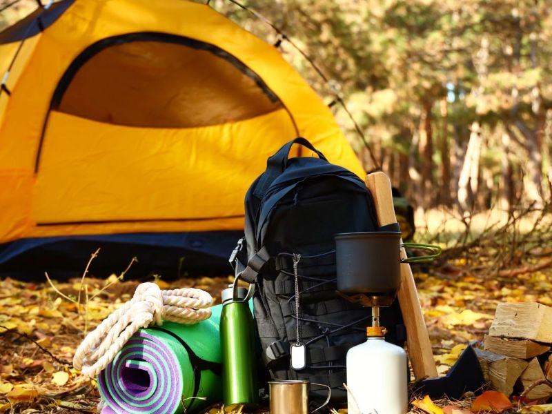 Ein Zelt im Wald, davor Camping-Zubehör.