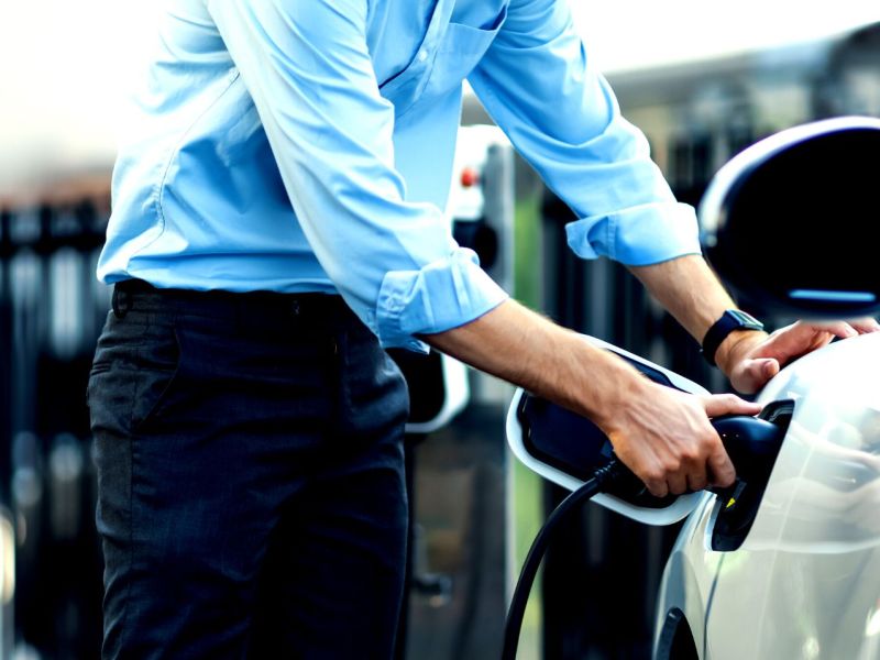 Mann lädt ein Elektroauto auf.