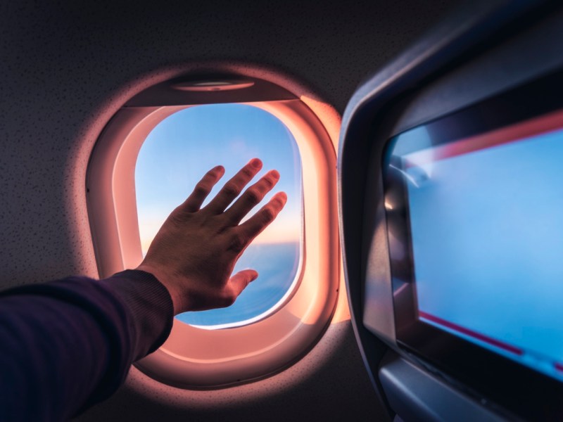 Hand am Flugzeugfenster