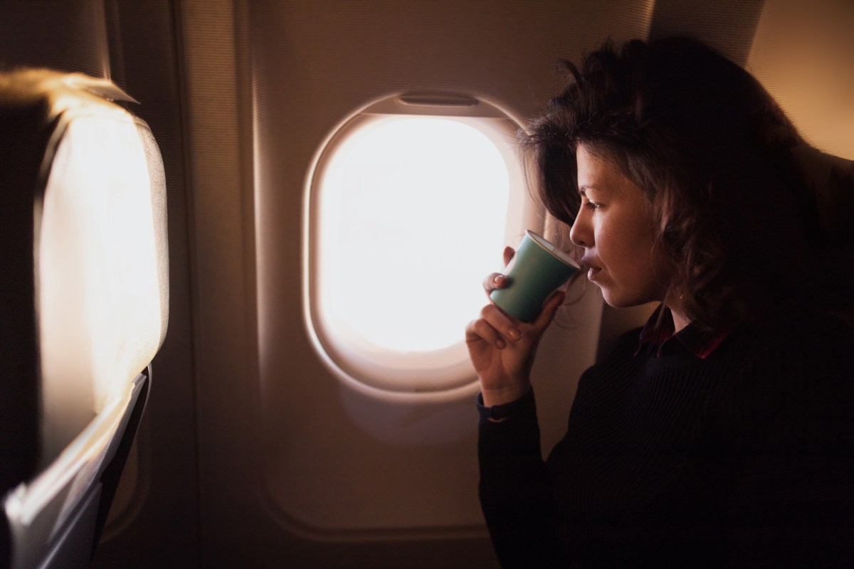 Frau trinkt Kaffee in Flugzeug