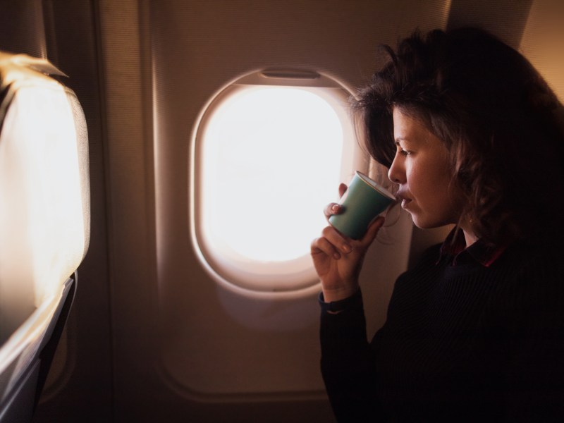 Frau trinkt Kaffee in Flugzeug