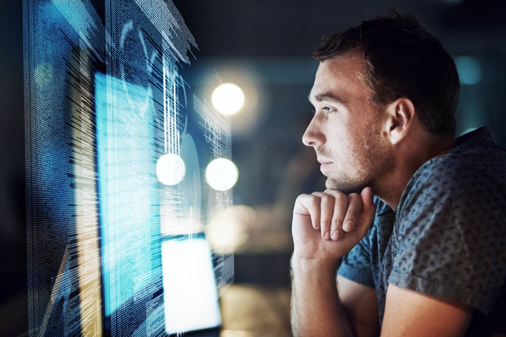 Mann sitzt vor dem Computer und analysiert Zahlen.