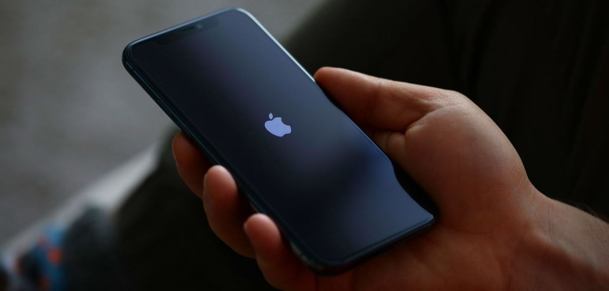 iPhone in der Hand mit Apple Logo
