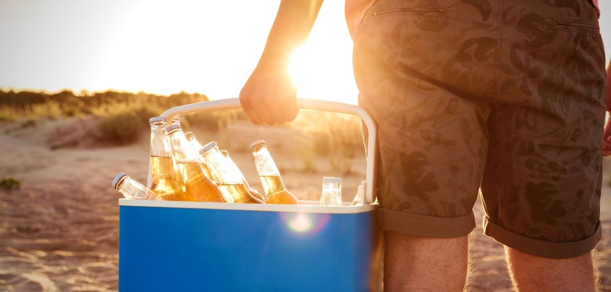 Mann mit Kühlbox am Strand