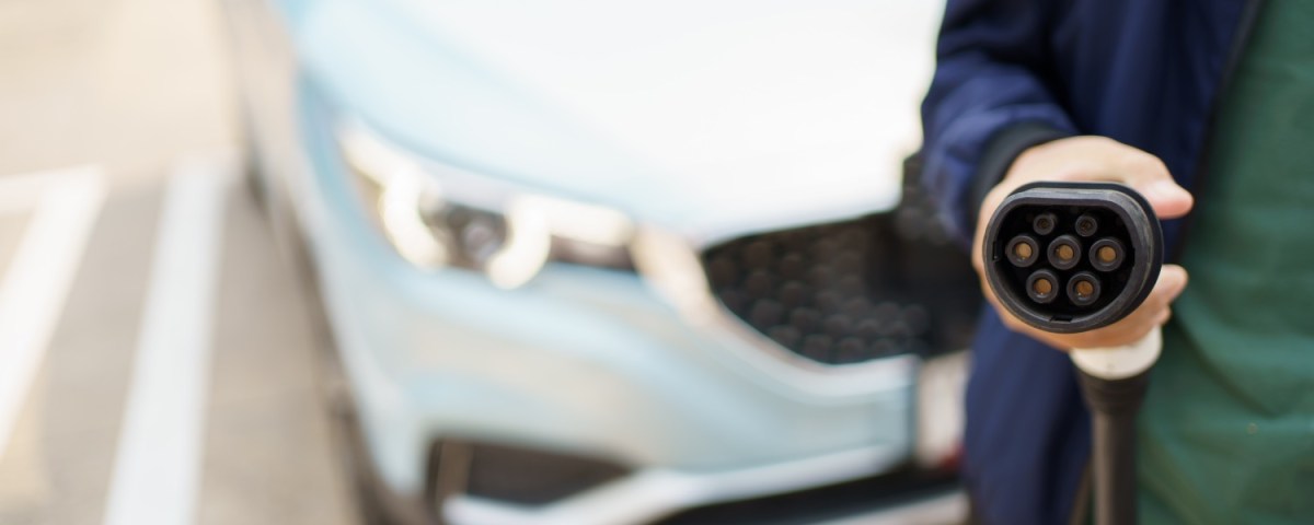 Mann hÃ¤lt Stecker eines Elektroautos in der Hand