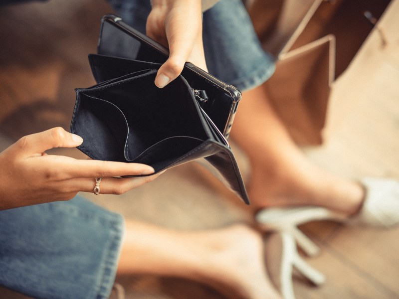 Frau hält ein leeres Portemonnaie in der Hand.