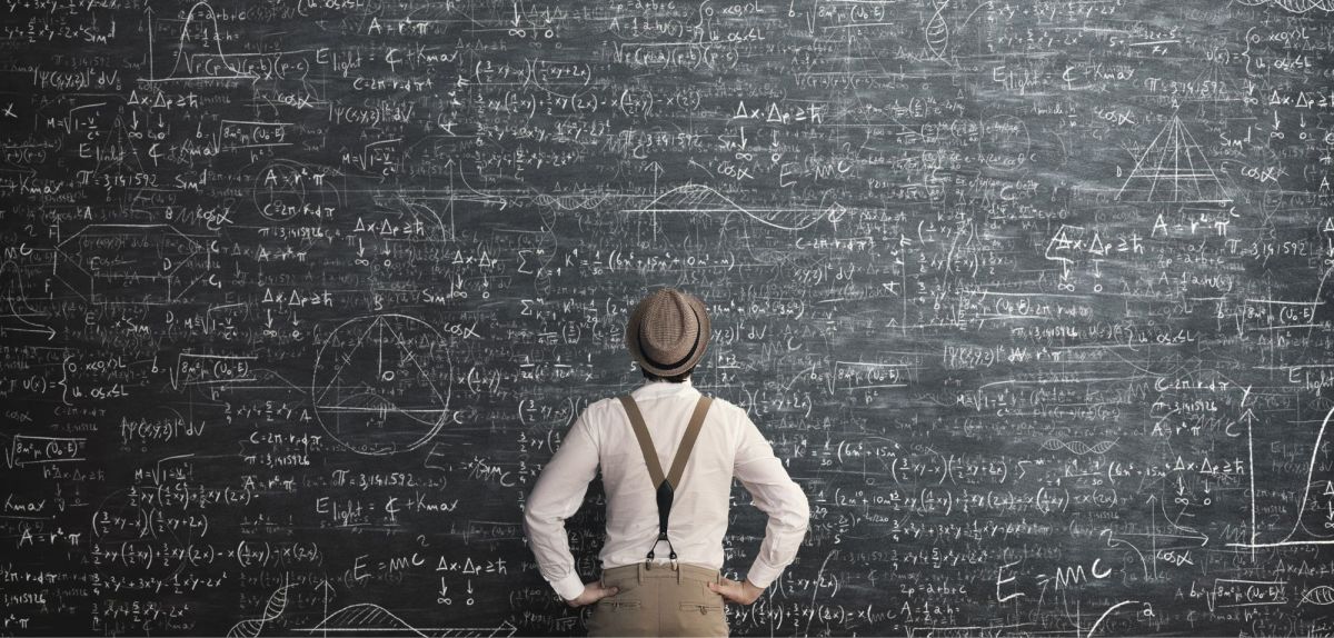 Mann steht vor einer Tafel mit mathematischen Formeln
