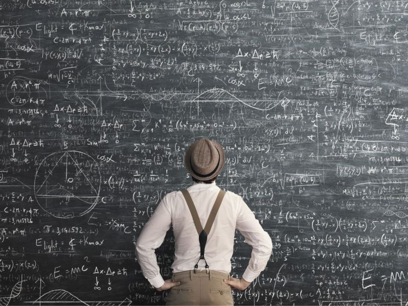 Mann steht vor einer Tafel mit mathematischen Formeln