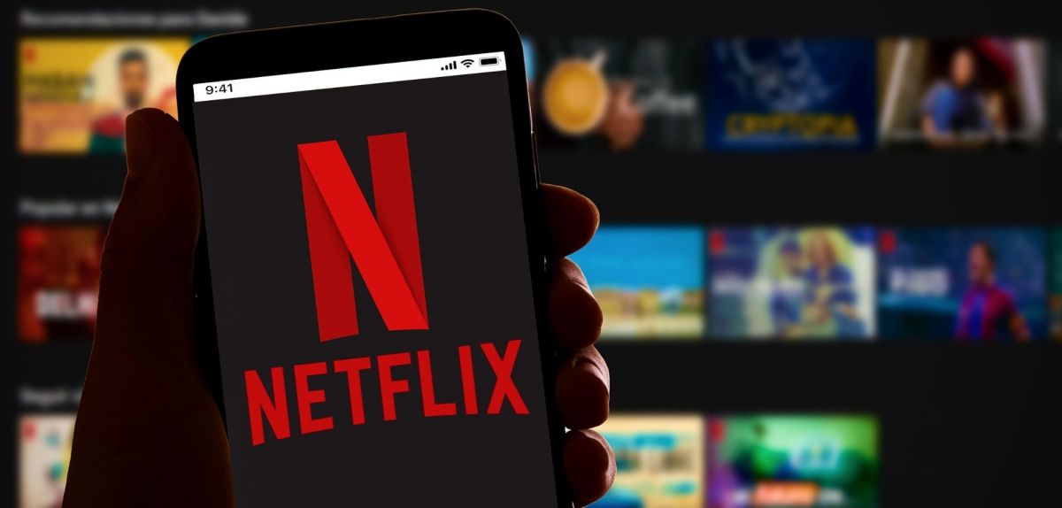 Handy mit Netflix-Logo, dahinter Streaming-Kacheln.