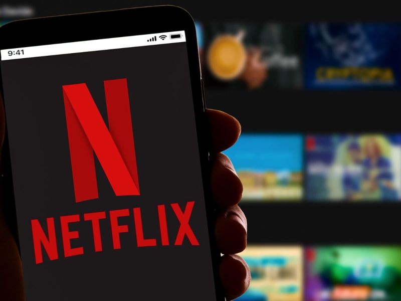 Handy mit Netflix-Logo, dahinter Streaming-Kacheln.