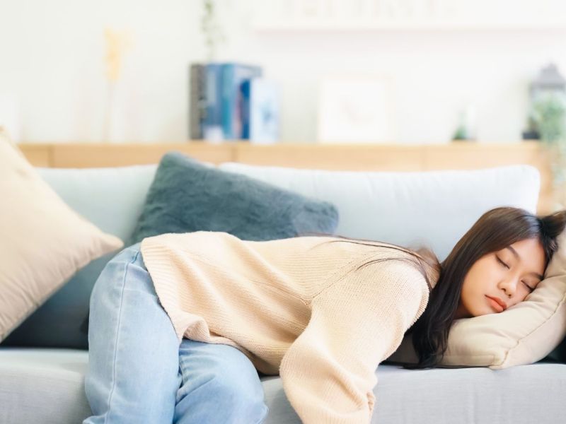 Frau hält auf einem Sofa ein Nickerchen.