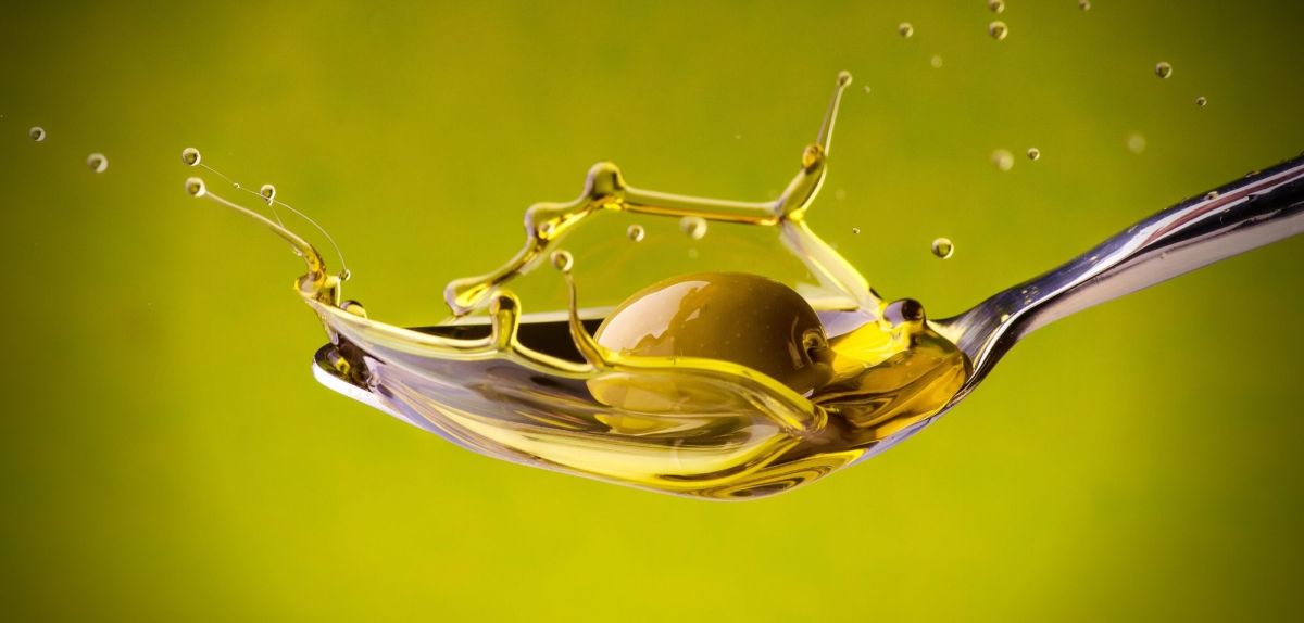 Ein Löffel Olivenöl samt Olive