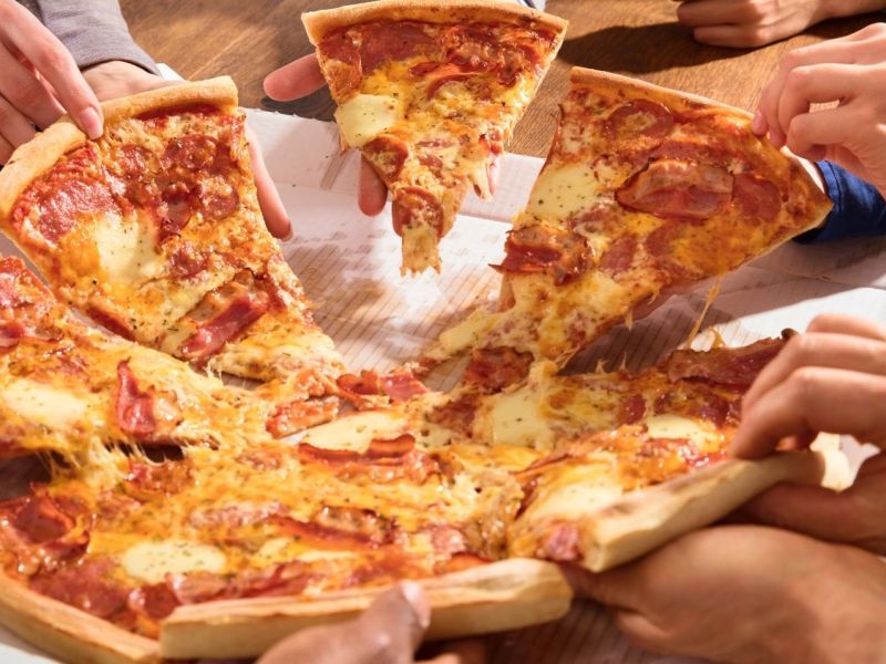 Mehrere Personen teilen sich eine Pizza.