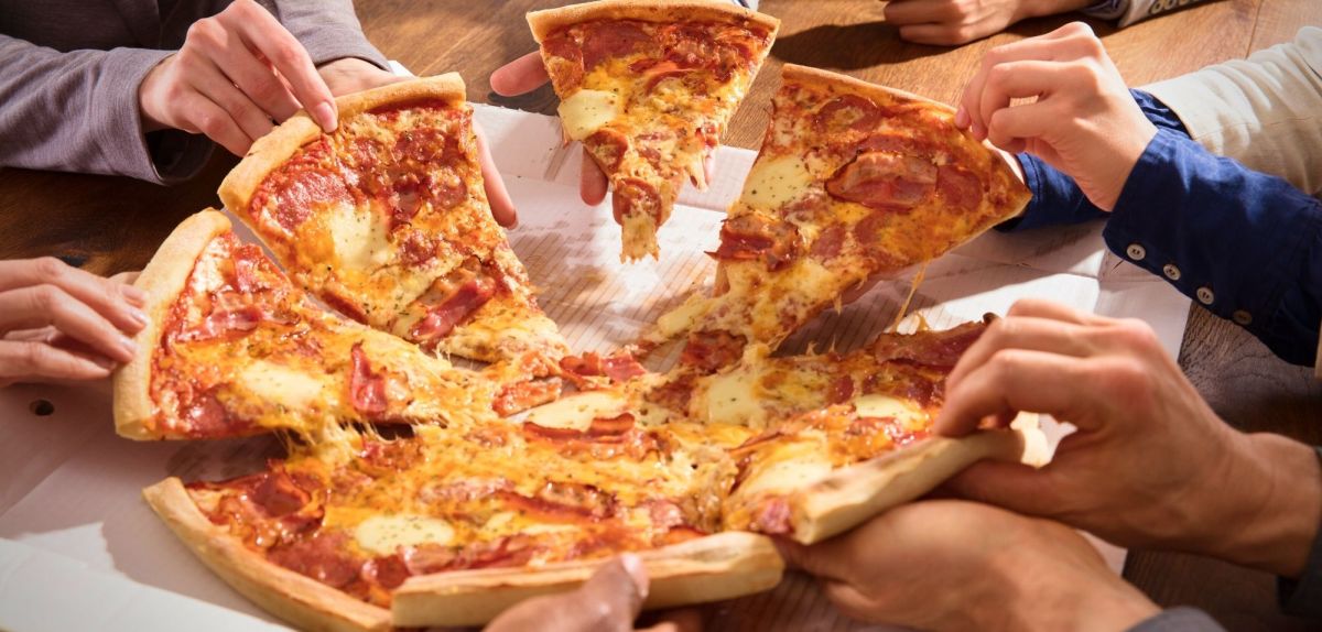 Mehrere Personen teilen sich eine Pizza.