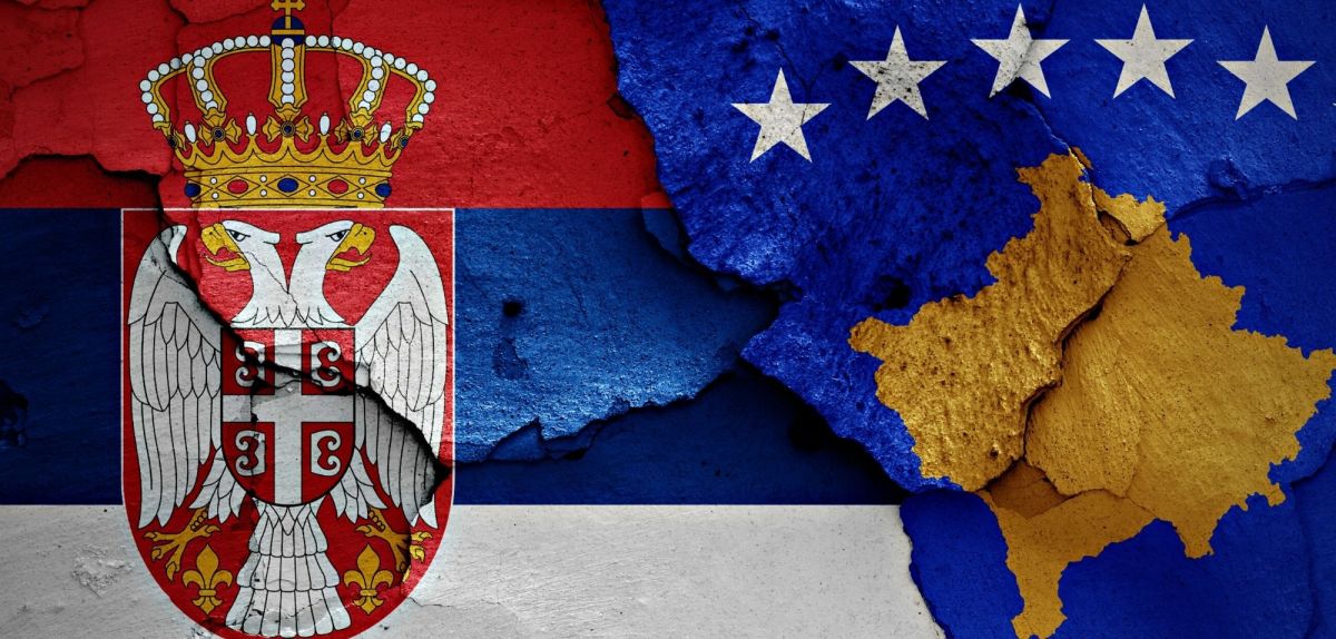 Die Flaggen Serbiens und des Kosovos auf einer rissigen Wand