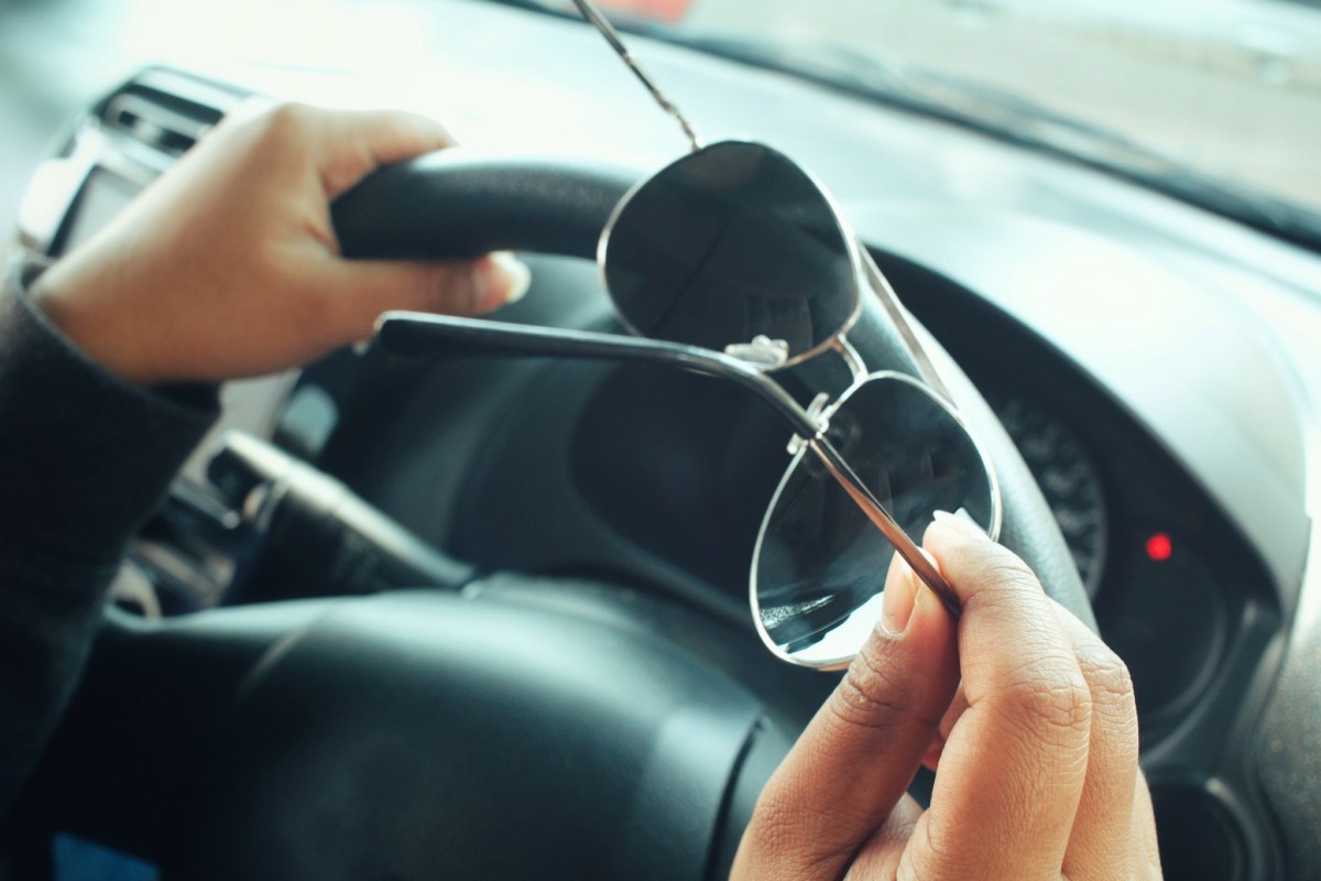 Mann am Lenkrad hält Sonnenbrille in der Hand