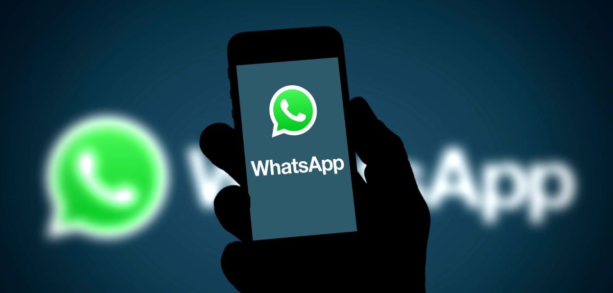 WhatsApp Logo auf dem Handy sowie im Hintergrund