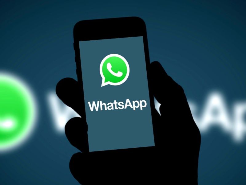 WhatsApp Logo auf dem Handy sowie im Hintergrund