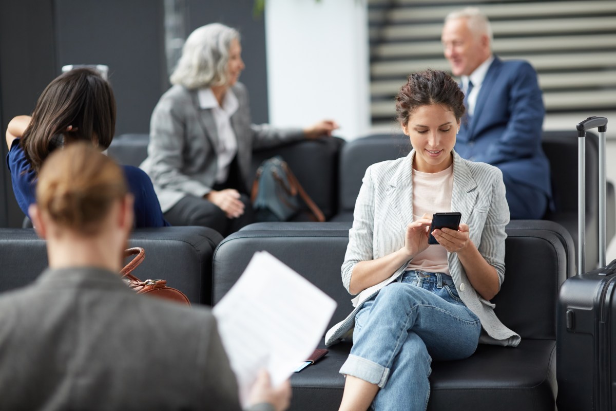 Frau surft am Handy am Flughafen