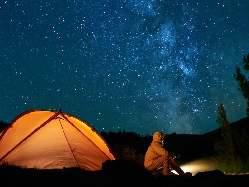 Camper mit Zelt unter dem Sternenhimmel.